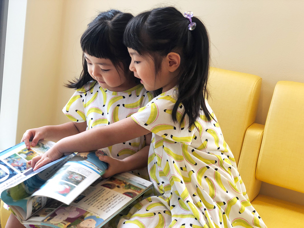 ２人の子どもが絵本をめくっているところ