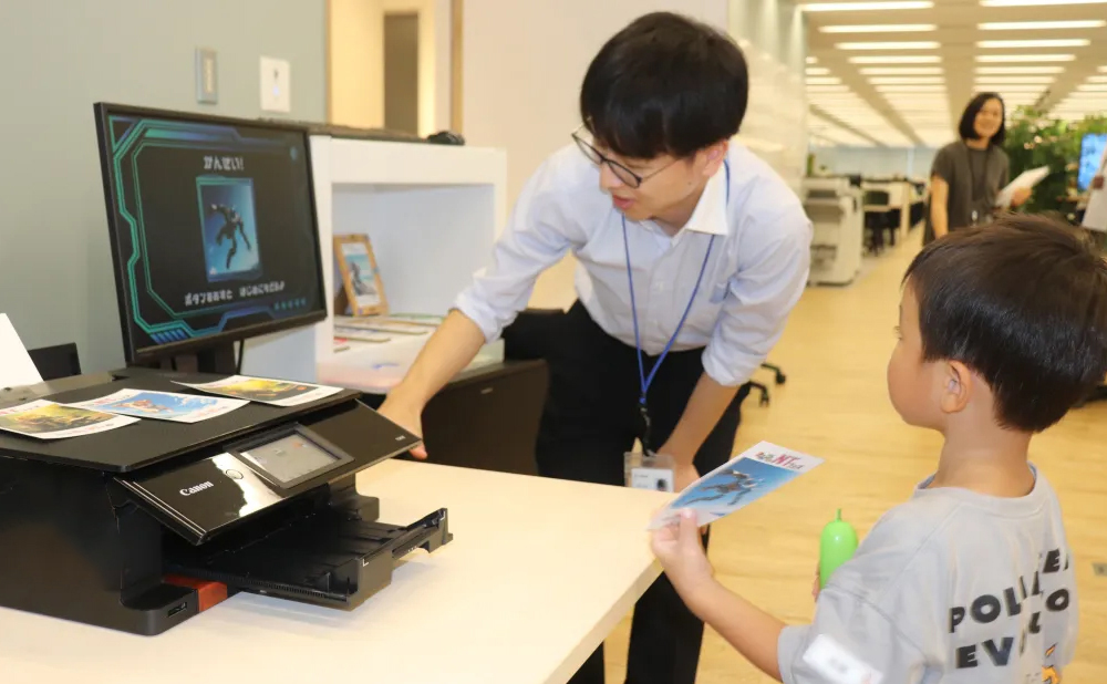 完成した「AIアート」をプリンターで出力するスタッフとそれを見つめる子ども