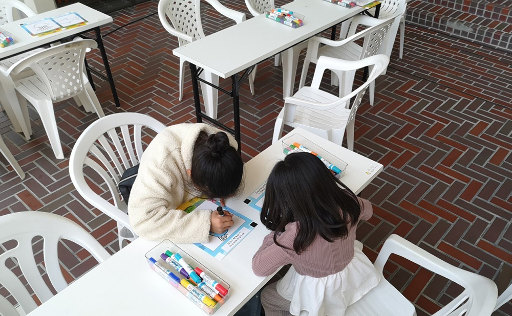 白いテーブルの上でぬりえをする子ども2人