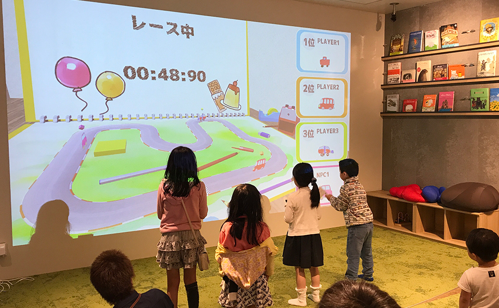 「おえかきパラダイスレース」の画面の前で子どもたちがコントローラーで遊ぶ写真